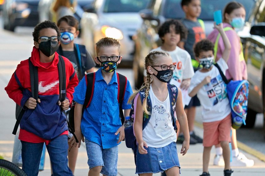 In this Tuesday, Aug. 10, 2021 file photo, Students, some wearing protective masks, arrive for the first day of school at Sessums Elementary School in Riverview, Fla.  AP Photo/Chris O'Meara, File