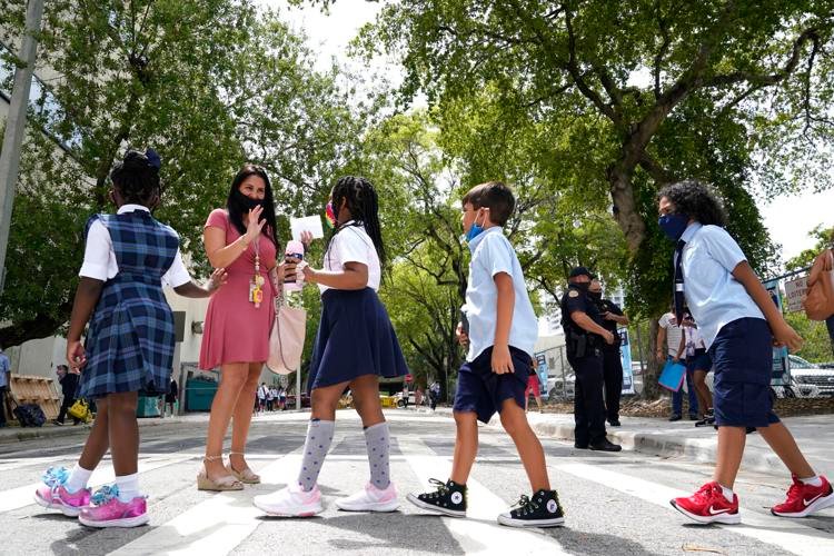 Teacher Vanessa Rosario greets students outside of iPrep Academy on the first day of school, Monday, Aug. 23, 2021, in Miami-Dade County. Schools opened with a strict mask mandate to guard against coronavirus infections. AP Photo/Lynne Sladky