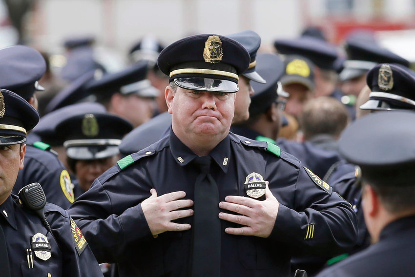 A police officer fights back tears at a memorial service.