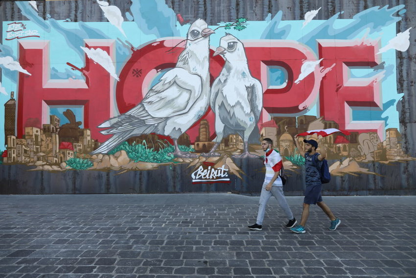 People walk past a wall mural of hope.