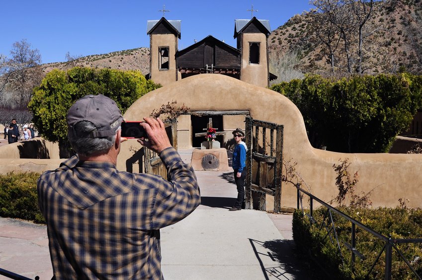 A tourist takes a photo of the Catholic chapel El Santuario de Chimayo in Chimayo, New Mexico.