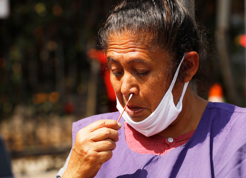 woman with lowered mask swabs her own nose
