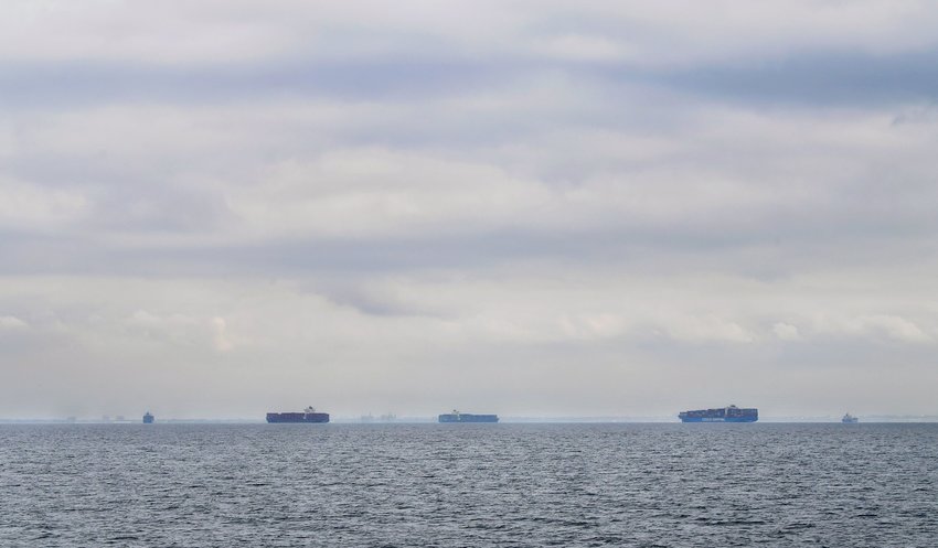 Cargo ships filled with containers idle in waters off of California on a cloudy day as they await entry to the Port of Los Angeles or Port of Long Beach