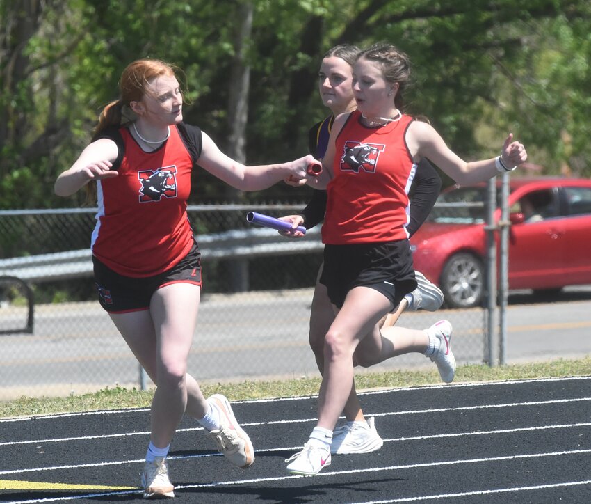 Norfork's Aimee Johnson (right) hands off to teammate Cassie Duffy during the 4x100 relay on Monday in the 1A-2 District track and field meet at Bomber Stadium.
