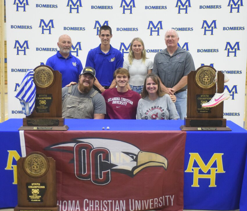 Mountain Home's Cade Triantos (front, middle), pictured with family and coaches, signed Monday at National Letter of Intent to run track and cross country at Oklahoma Christian University.