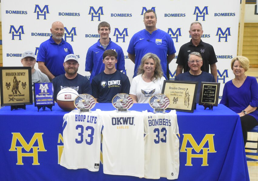 Mountain Home basketball standout Braiden Dewey (seated, third from left), pictured with family and coaches, signed a National Letter of Intent to play at Oklahoma Wesleyan University.