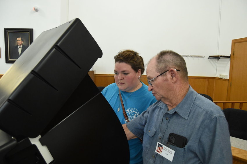 Voter Haley Himstedt (left) listens as poll worker Ezra Roberts tells her how to use the voting machine Monday afternoon at the Baxter County Courthouse. A total of 332 Baxter County residents voted early Monday, with another 141 residents voting early in Marion County.