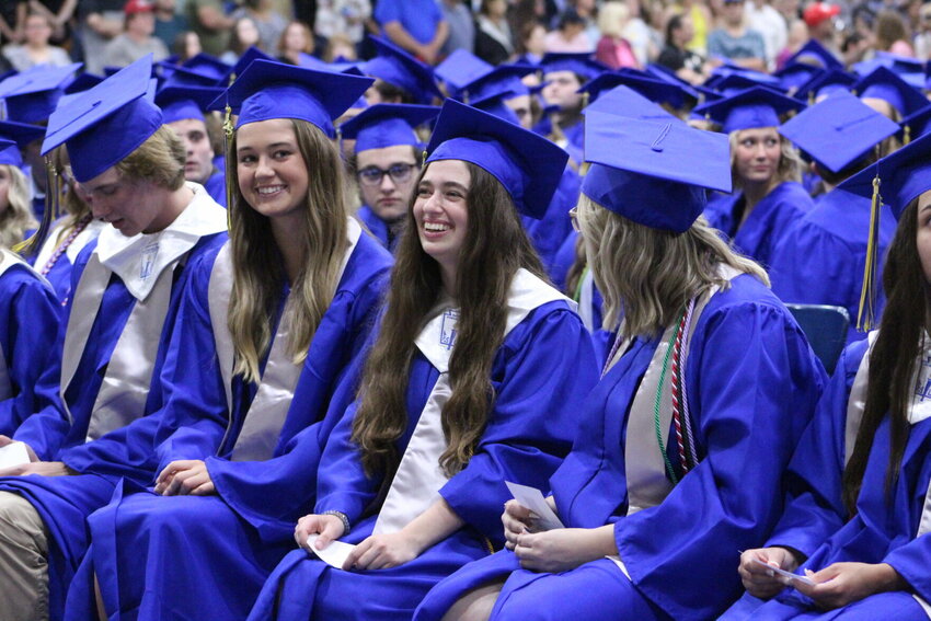 Mountain Home graduates Trevi Sheaner (center) and Amelia Rucker (left) are all smiles during the Mountain Home High School graduation cermony Friday night at &quot;The Hangar.&quot;   Ethan Granniss/Special to The Bulletin
