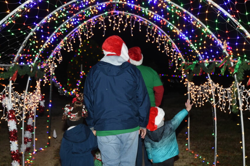 Visitors walk through a trellis full of lights at a previous Christmas in Cotter holiday event at Big Spring Park. The annual event returns from 5-7 p.m. Saturday.   Bulletin File Photo