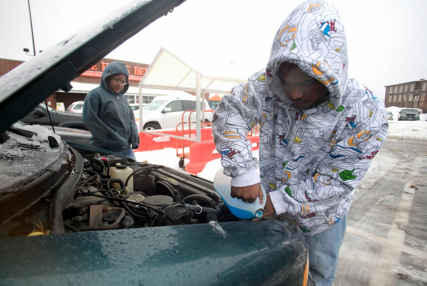 Vivian Rodriguez (left) watches as Victor DeJesus, of Pawtucket, R.I, fills up his windshield washer fluid in the parking lot of a home improvement store in Providence, R.I.   Stew Milne/AP File Photo