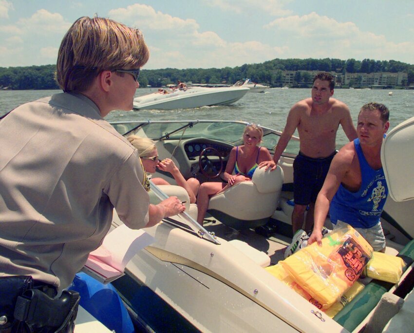 In this file photo, a man shows his life preservers to Missouri State Water Patrol Officer Stacey Mosher on the Lake of the Ozarks near Osage Beach, Mo. Mosher pulled him over for creating a wake in a no-wake zone under a bridge, but just issued a warning. She also suggested he remove the preservers from their plastic bags.   Cliff Schiappa/AP File Photo
