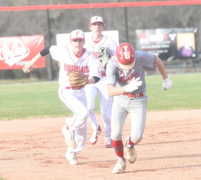 Flippin shortstop Truett Lindsey chases a Green Forest player in a rundown during a recent home game. Also pictured is second baseman Blake Henley.