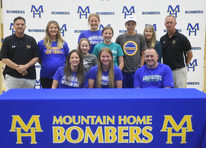 Mountain Home's Ava Fosness (front, center), pictured with family and coaches, signed Monday a letter of intent to play college softball at Arkansas State University-Mountain Home.