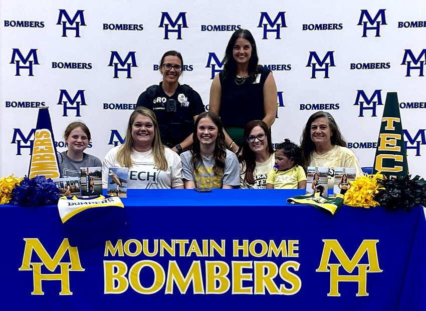 Mountain Home's Jaidyn McCurley (seated, third from left), pictured with family and coaches, signed Monday a letter of intent to join the cheerleading program at Arkansas Tech University in Russellville.