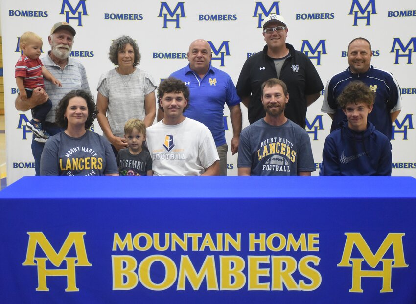 Mountain Home's Corwin Morris (front, third from left), pictured with family and coaches, signed recently to play college football at Mount Marty University in South Dakota.