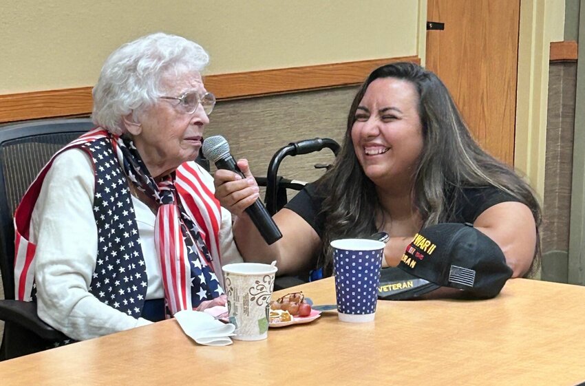 Hollie Scoma (right) holds the microphone for 102-year-old Edith Mitchell during her address to the Baxter County Historical Society. Mitchell served in World War II as a member of the Women's Army Corps.   Caroline Spears/The Baxter Bulletin