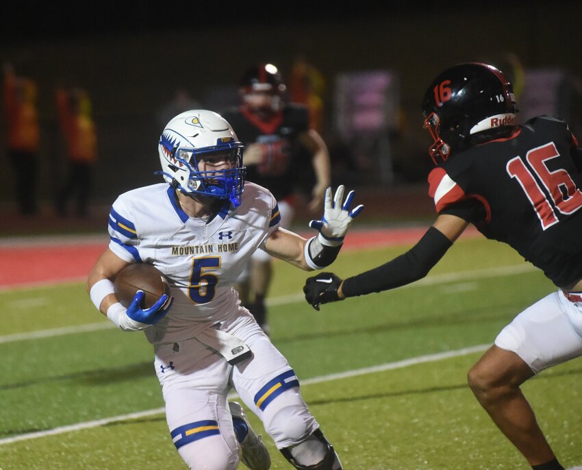 Mountain Home's Barrett Miller prepares to stiff-arm a defender during the Bombers' 34-14 win over Russellville on Friday.