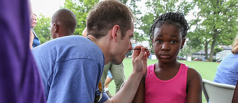 Colton Jones, a member of Crossroads Church in Newnan and one of 51 students from Southwestern Seminary in Forth Worth, TX who traveled to Columbus, Ohio for Crossover 2015, paints the face of a young girl at a block party June 13 at Cassingham Elementary School. The evangelistic event, sponsored by Paramount Church in Columbus, was part of Crossover 2015 held prior to the June 16-17 Southern Baptist Convention annual meeting at the Greater Columbus Convention Center. ADAM COVINGTON/Special