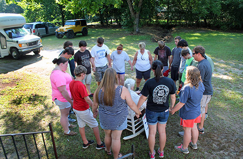 Gresston Baptist Church youth and their leaders surround and pray for a homeowner for whom they had just completed a major renovation as part of their SPLASH community-service mission project. JENNIFER LEE/Special