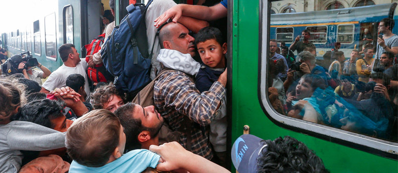 Refugees storm into a train at the Keleti train station in Budapest, Hungary, Sept. 3. as Hungarian police withdrew from the gates after two days of blocking their entry. In the wake of the Paris attacks, a new debate has sprung up on allowing Syrian refugees into the U.S., with at least half of the states' governors vowing to refuse access. Freedom House/Flickr