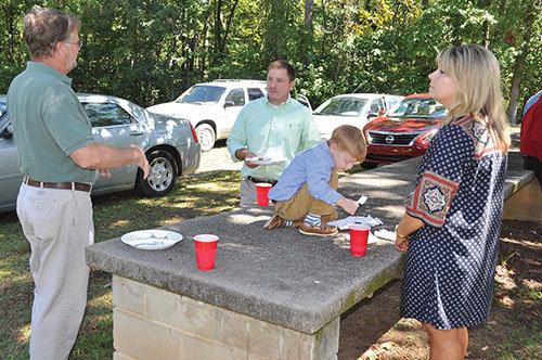 Members visit around the old concrete picnic tables during the covered dish lunch. Eating outdoors under the shade trees provided a pleasant option to the densely packed fellowship hall rooms. JOE WESTBURY/Index