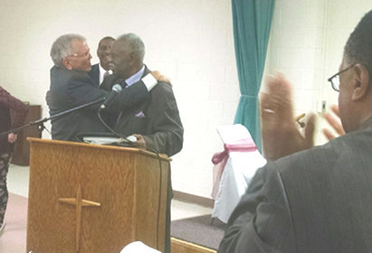 At a 2015 racial reconciliation event hosted by the SBC National African American Fellowship, SBC executive David Waltz, left, hugged NBCUSA pastor emeritus Gus Roman. NAAF President K. Marshall Williams stands behind them. BP/Photo