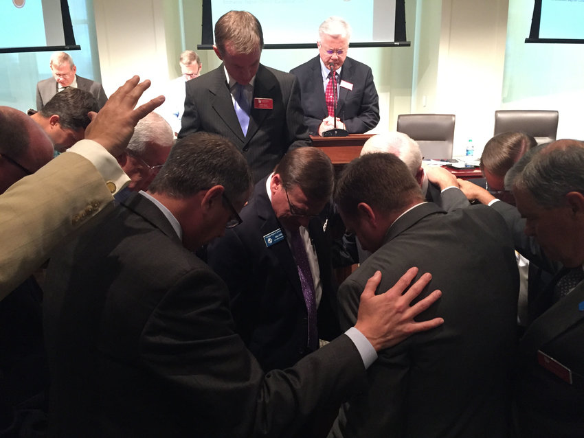 Members of the Executive Committee lay hands on Griffin, center, in an impromptu emotional ceremony. Wayne Robertson of Morningside Baptist Church in Valdosta, at the lectern, led in prayer for Griffin's ministry in promoting religious liberty legislation. JOE WESTBURY/Index 