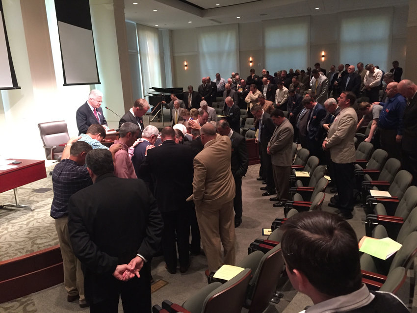 Members of the Executive Committee stand while others surround Griffin in prayer. JOE WESTBURY/Index