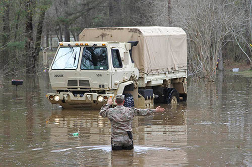 Sgt. David Breaud of Deville, LA with Headquarters and Headquarters Company 225th Engineer Brigade directs a high water vehicle down a flooded roadway at Iatt Lake in Grant Parish, La., Mar. 13, 2016. (U.S. Army National Guard photo by Staff Sgt. Jerry Rushing)
