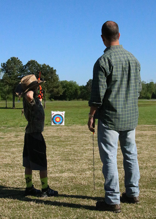 Seven-year-old Zeke Helton aims his bow under the eye of his dad, Shep. SCOTT BARKLEY/Index