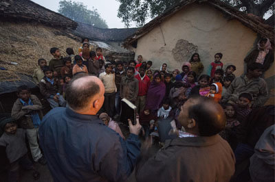 At dusk, IMB missionary Mitch Englehart (left, name changed) teaches and share with locals at his last stop of the day, a small South Asian village. PAUL LEE/IMB