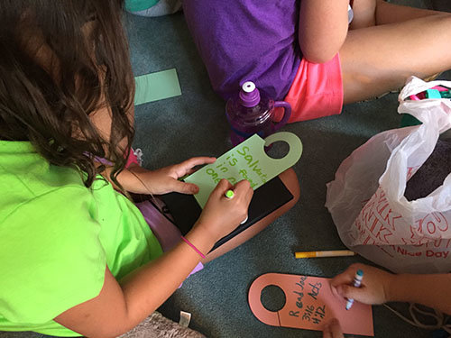 One of the activities was making door hangers which Bryan and Leisa Catherman would take back to Utah as they continue their ministry in the neighborhoods. The girl on the left is writing "Salvation is only found in the name of Jesus" while the girl on the right is writing "Read John 3:16 and Acts 4:12." JOE WESTBURY/Index