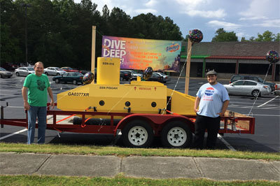Deacon Steve Phillips, left, and Matthew Henry, right, have displayed the submarine at local businesses who not only benefit from the oddity but allow the church to promote Vacation Bible School as well. Henry is son of sub builder and retired naval officer Kevin Henry. MOUNT PISGAH/Special