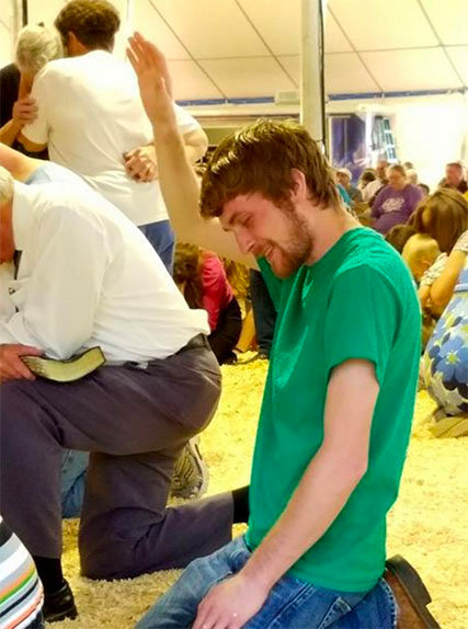 A young man kneels to pray at the revival on July 19. MICHAEL D. ABERNETHY/Times-News Burlington,NC