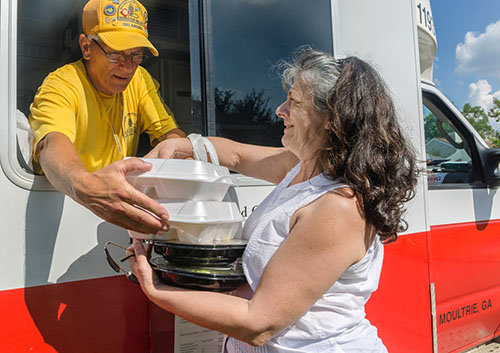 Southern Baptist Disaster Relief team member Jerry Ritter, a member of Blackgum First Baptist Church in Vian, OK, hands two hot meals to flood survivor Pat Thomas, a member of Healing Place Church of Baton Rouge. The SBDR kitchen where Ritter is serving began preparing an average of 14,000 meals per day to aid survivors of flooding in south Louisiana in mid-August. CARMEN K. SISSON/NAMB