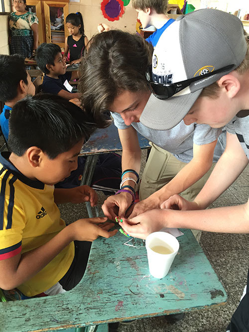 Volunteer students help a child make a gospel bracelet to explain salvation in Christ. KATHY EUDY/Special