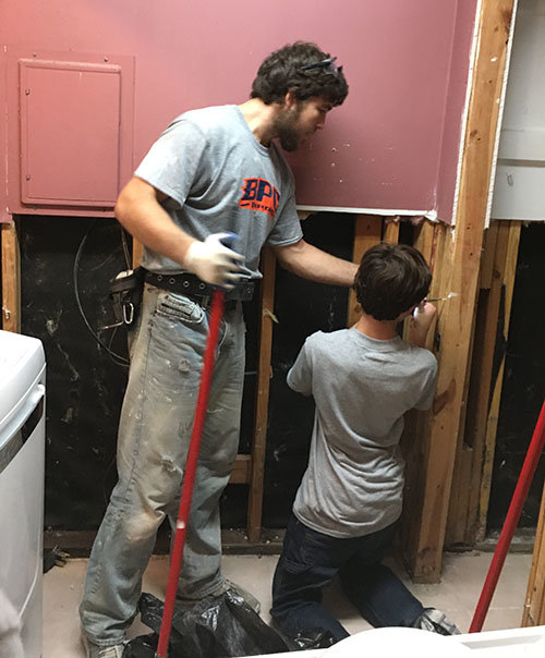 Nate Pristavec, standing, and William Puckett remove sheetrock and insulation ruined by flood waters. BPC/Special