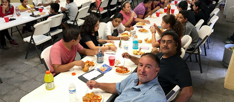 Rolando Ruiz, lower right in blue shirt, and Samuel Rodriguez, in black shirt, pause during an afternoon meal in the church fellowship hall. JOE WESTBURY/Index