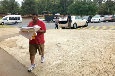 Carlos Abad, a member of Primera Iglesia Bautista Hispana in Savannah church, helps carry in food donated from a sister church. Ruiz and Rodriguez said the community has been very generous in accommodating the evacuees. The Gwinnett Metro Baptist Association also provided financial assistance to offset feeding costs. JOE WESTBURY/Index 