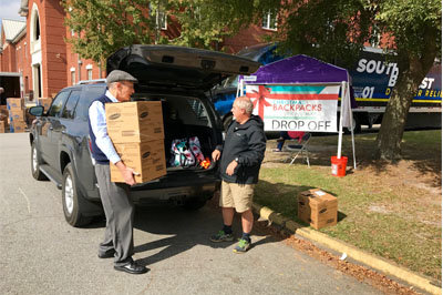 Jim Shaffer, right, delivers a carload of backpacks to Bill Barker at the collection site behind Calvary Baptist Temple. Barker is director of Appalachian Regional Ministries and Schaffer was delivering the items collected by the MOPS ministry at Kennesaw First Baptist Church. JOE WESTBURY/Index