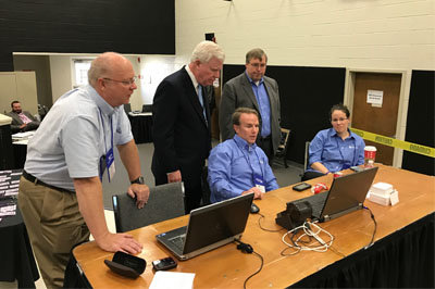 Georgia Baptist Mission Board Executive Director J. Robert White, standing center, and Kevin Smith, vice president for operation, right, monitor messenger registration from State Missionary Kevin Wilson, seated, who implemented the new online registration process. Looking on is State Missionary Bryan Nowak, far left, and State Missionary Alicia Simpson, seated to the right. JOE WESTBURY/Index