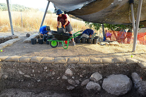A worker loads a wheel barrel full of excavation debris.
