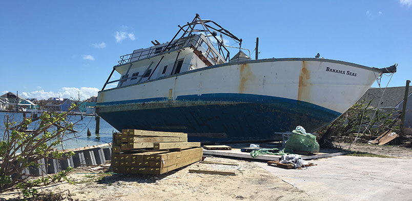 A boat damaged and left on shore.
