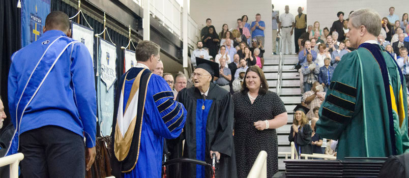 Shorter University President Don Dowless congratulated Horace Sheffield on receiving his degree as the crowd gives a standing ovation. Standing at right is Amanda Brannock, a neighbor who was invited to Sheffield's church soon after she moved to Georgia. Brannock's husband and son were both baptized through Sheffield's ministry, she said. DAWN TOLBERT/Shorter