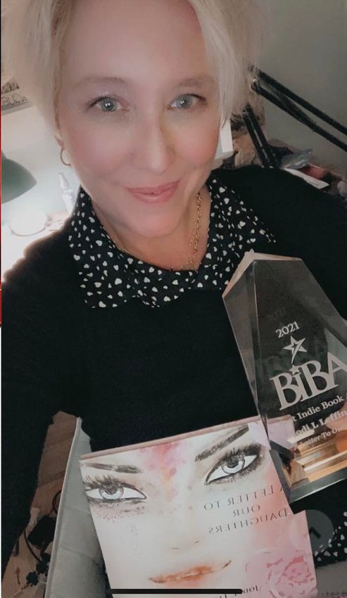 Dr. Jodi L. Leffingwell holding a copy of her book, &lsquo;A Letter To Our Daughters&rsquo; and the 2021 BIBA award for non-fiction.