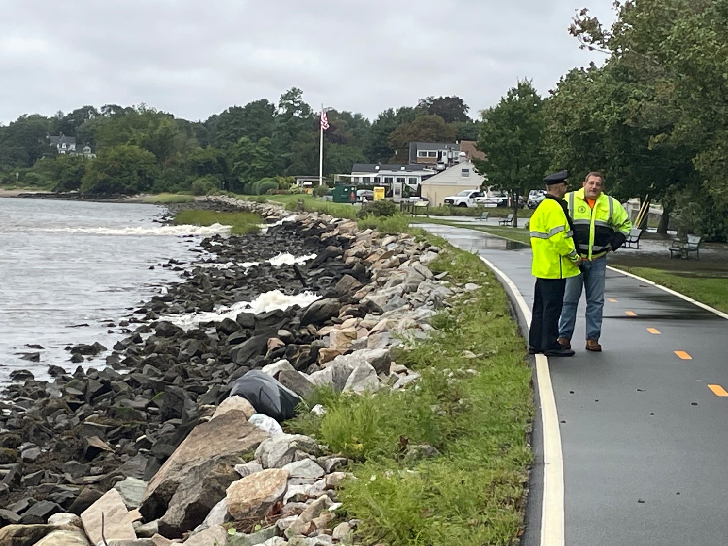 Brian Burke of the Bristol Police Department and John Olson of the RI Department of Transportation, survey the flooded area at Hope and Washington Streets. On the shoreline, floodwaters jet into Bristol Harbor from three separate pipes.