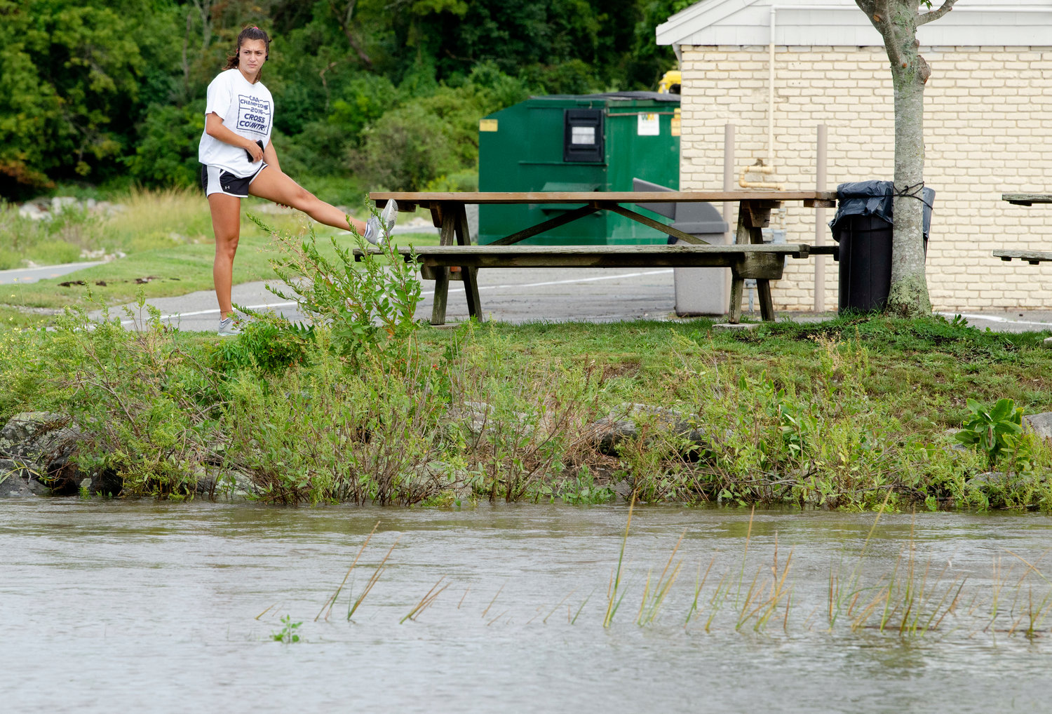 Runner, Karina Tavares, stretches out above Silver Creek overflowing it's banks into Bristol Harbor.