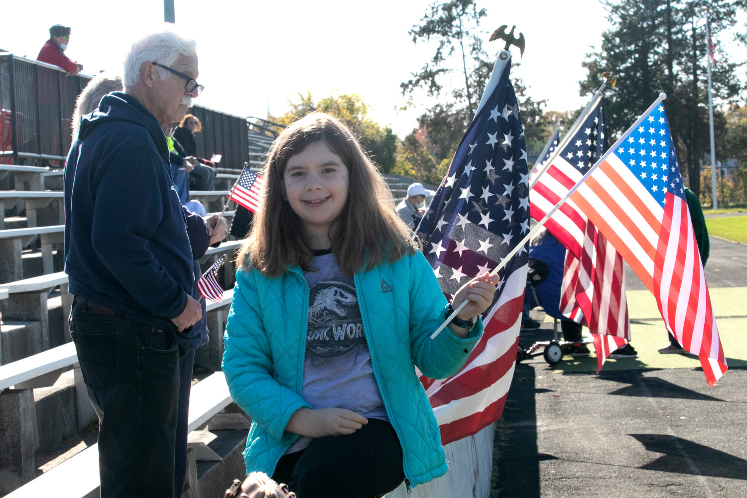 Madeleine Bentley, great grand daughter of Manuel J. Amaral, the eldest of the five Amaral Brothers who all served together in the US Navy during WWII, waves a flag during the ceremony. The Amaral Brothers Bridge on Veterans Memorial Parkway is named in their honor.