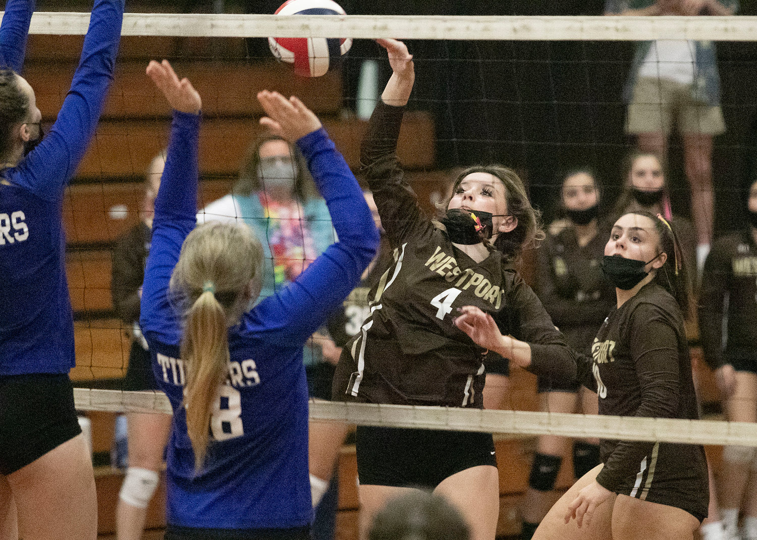 Middle hitter Zoey Sylvain taps the ball over the net with Abby Gaudreau looking on at right.