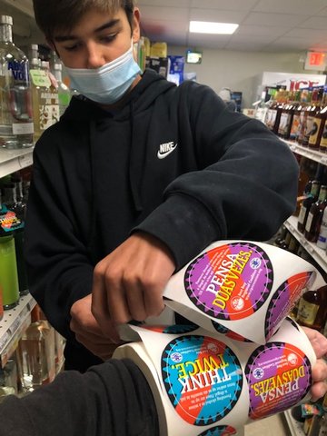 Brandon Doherty pulls stickers from a fresh roll to place on bottles and boxes of alcohol during Project Sticker Shock.